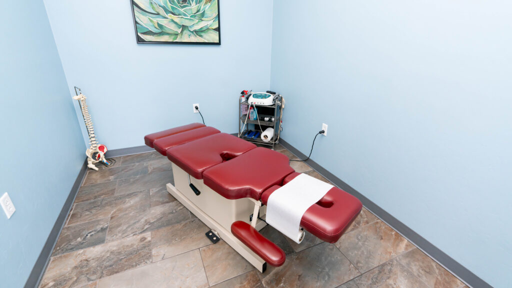 Chiropractic Adjustment Table at Ornelas Chiropractic in Tucson Chiropractic adjustment table in a clean, well-lit treatment room with a spinal model and chiropractic tools, showcasing a professional and welcoming environment for patients in Tucson.