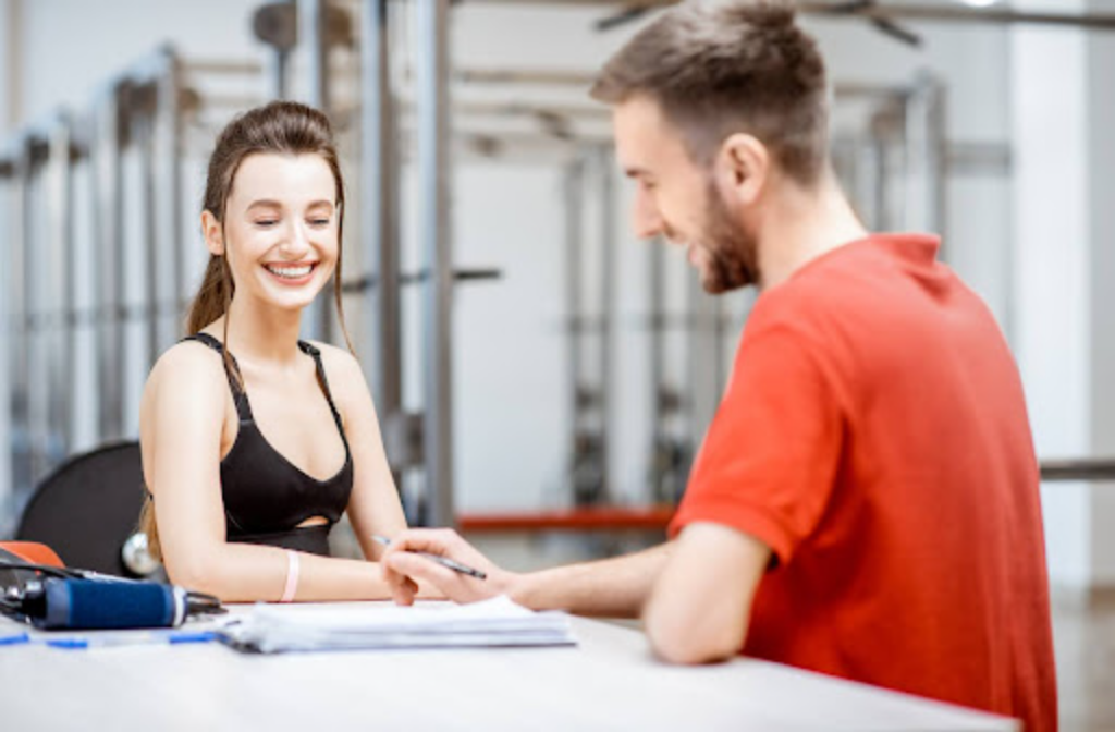 Smiling female athlete consulting with a sports chiropractor in a gym setting.