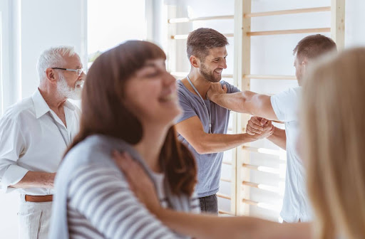 A group of people in a wellness setting smiling and engaging in a light chiropractic or physical therapy session, highlighting relaxation and stress relief.